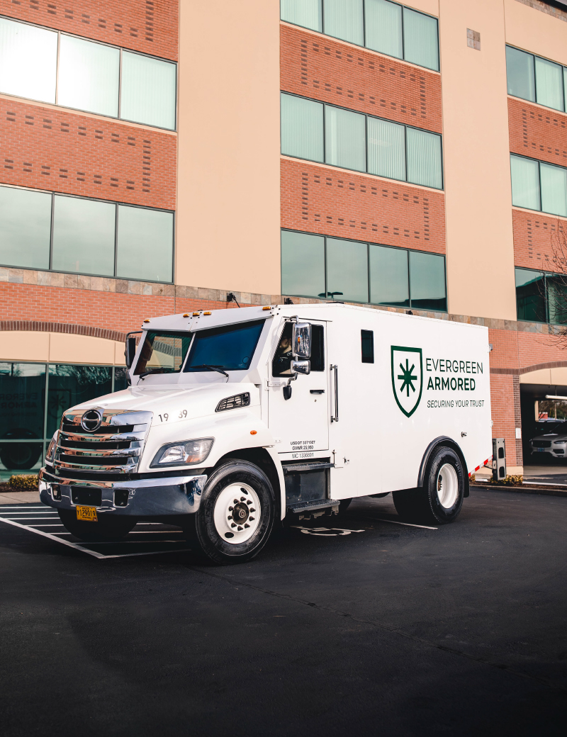 Evergreen Armored truck with tall building in background